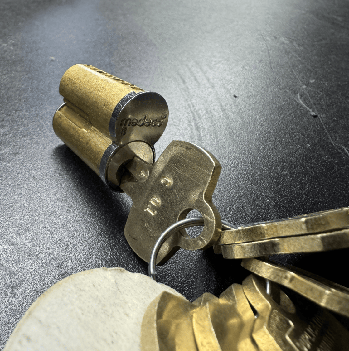 Close-up of a brass Medeco small format interchangeable core (SFIC) with a control key inserted, ready for removal or installation.